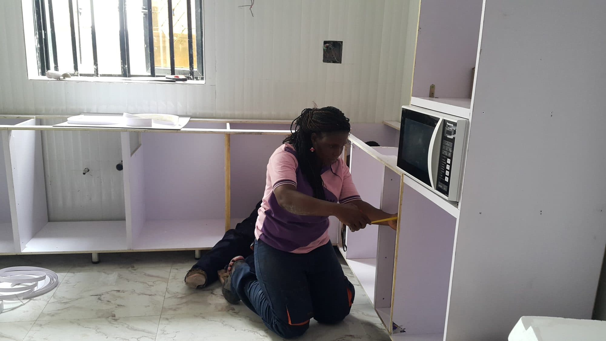 Installer fitting kitchen cabinets during a remodel