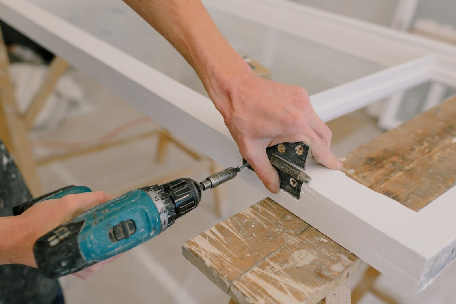 Handyman driving a screw into a cabinet hinge